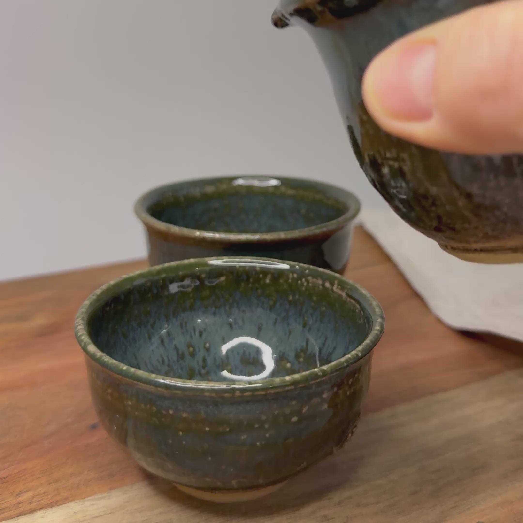 nalewanie herbaty z shiboridashi do czarek,
pouring japanese green tea from handmade shiboridashi during tea ritual, ceramic tea ceremony set